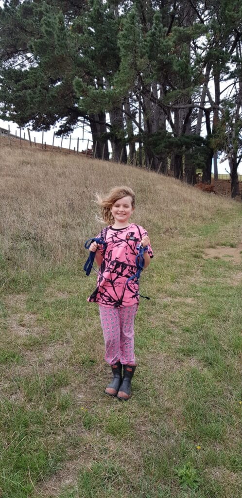Little gorm in pink fleece camo walking down a grassy path