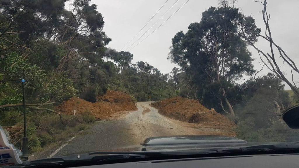 View of a road next to a bank with soil over most of the road down from bank with a meandering path the width of the car