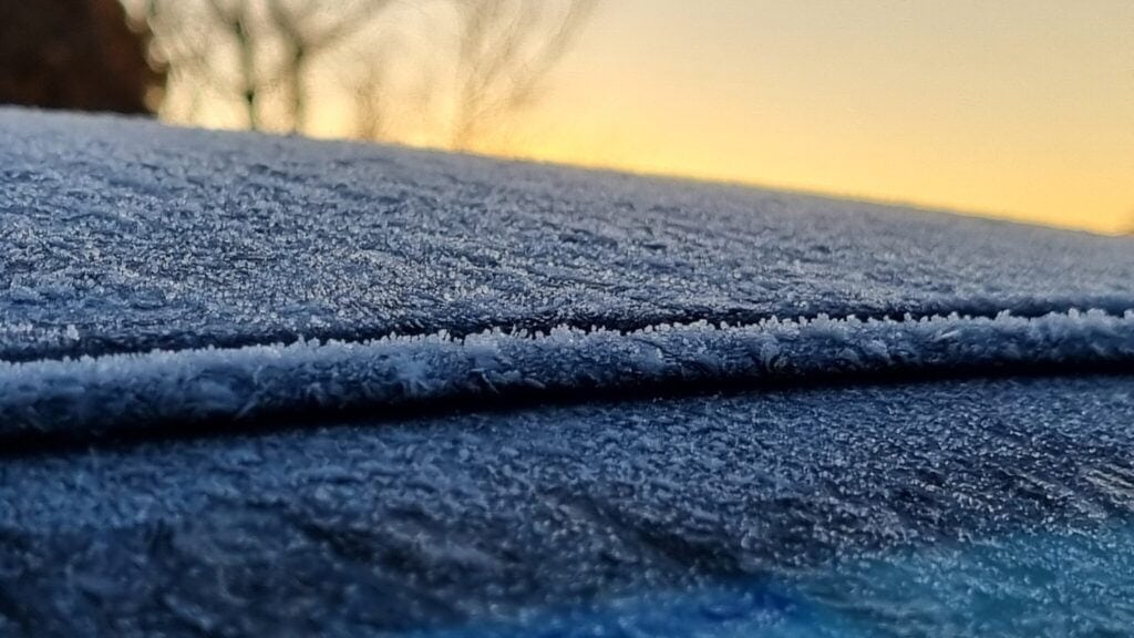 Ice crystals on the roof of a car with blurry landscape in the back