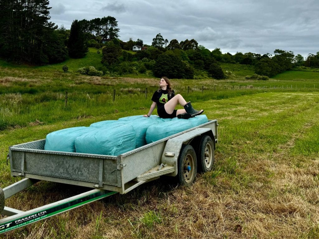 Person sitting on bales at back of trailer, posing like a supermodel